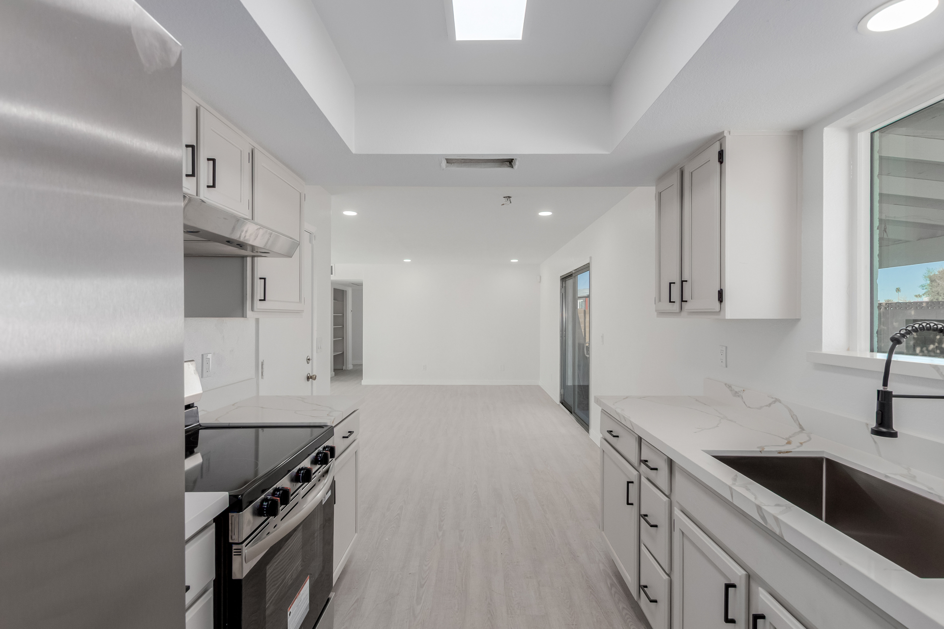 Remodeled galley kitchen with white shaker cabinets, quartz countertops, and matte black hardware