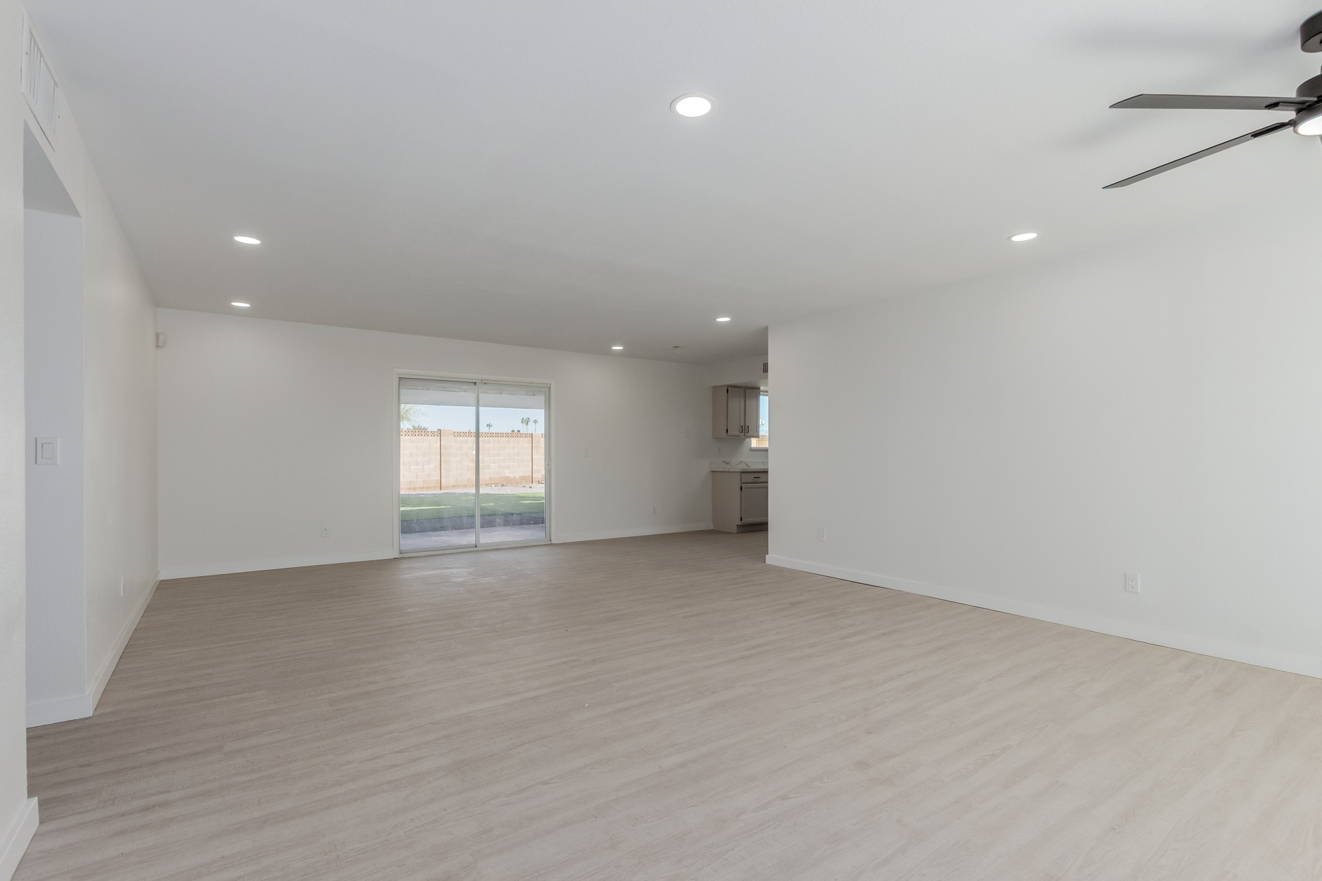 Spacious living room with light wood-look flooring and recessed lighting