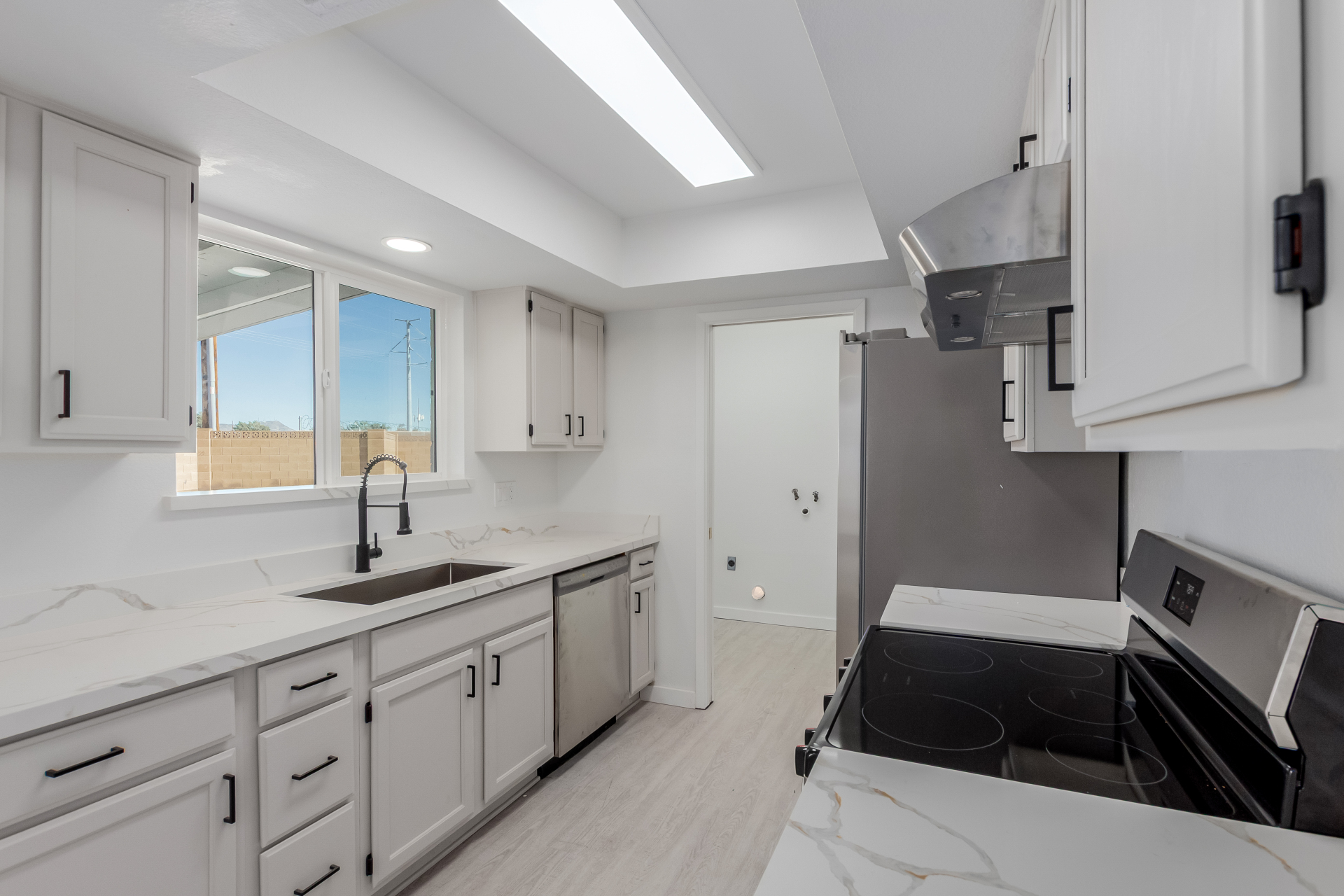 Bright kitchen remodel with skylights, quartz counters, stainless appliances, and matte black fixtures